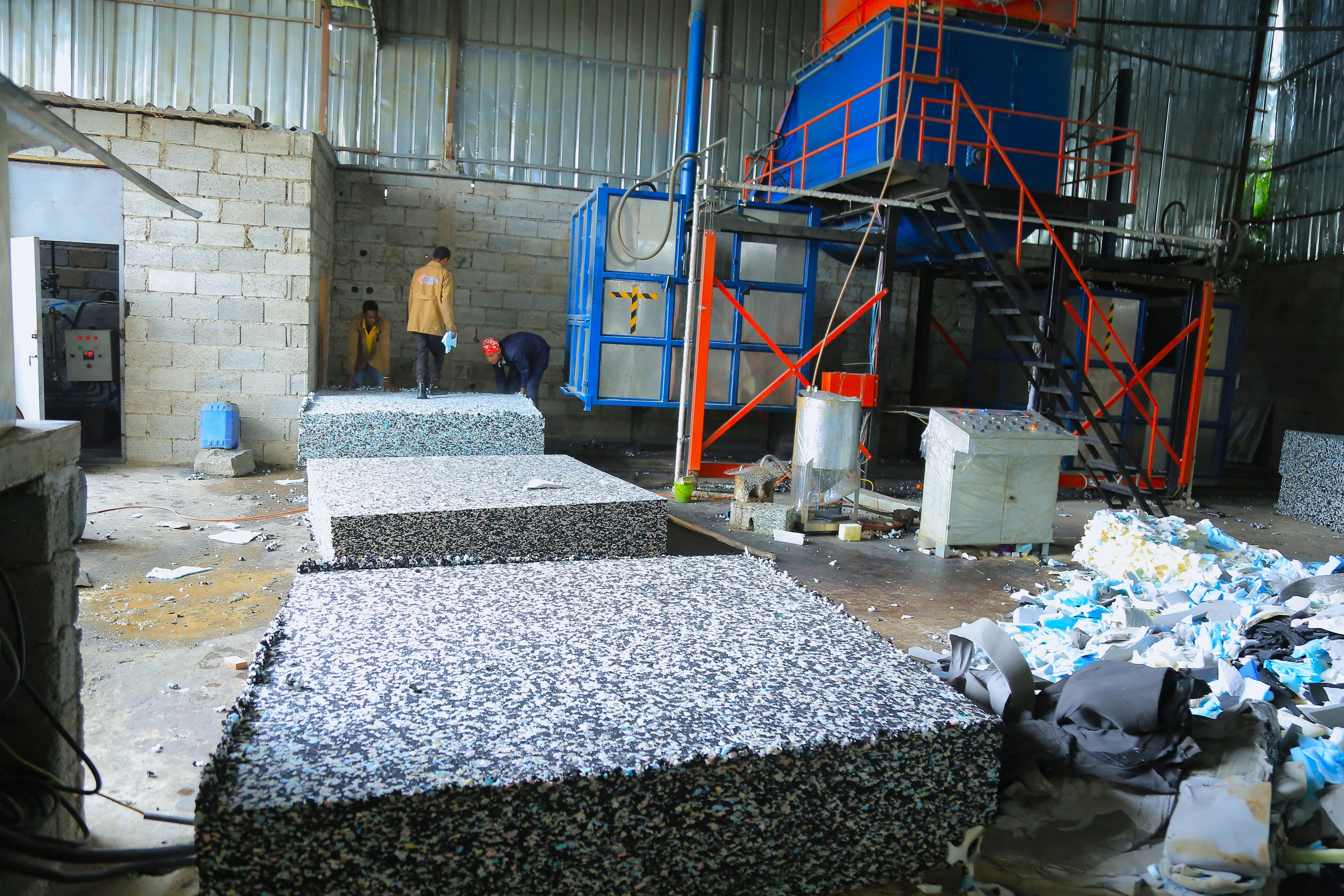 Bonded foam production area with foam scraps scattered around and a finished block resting on the floor.